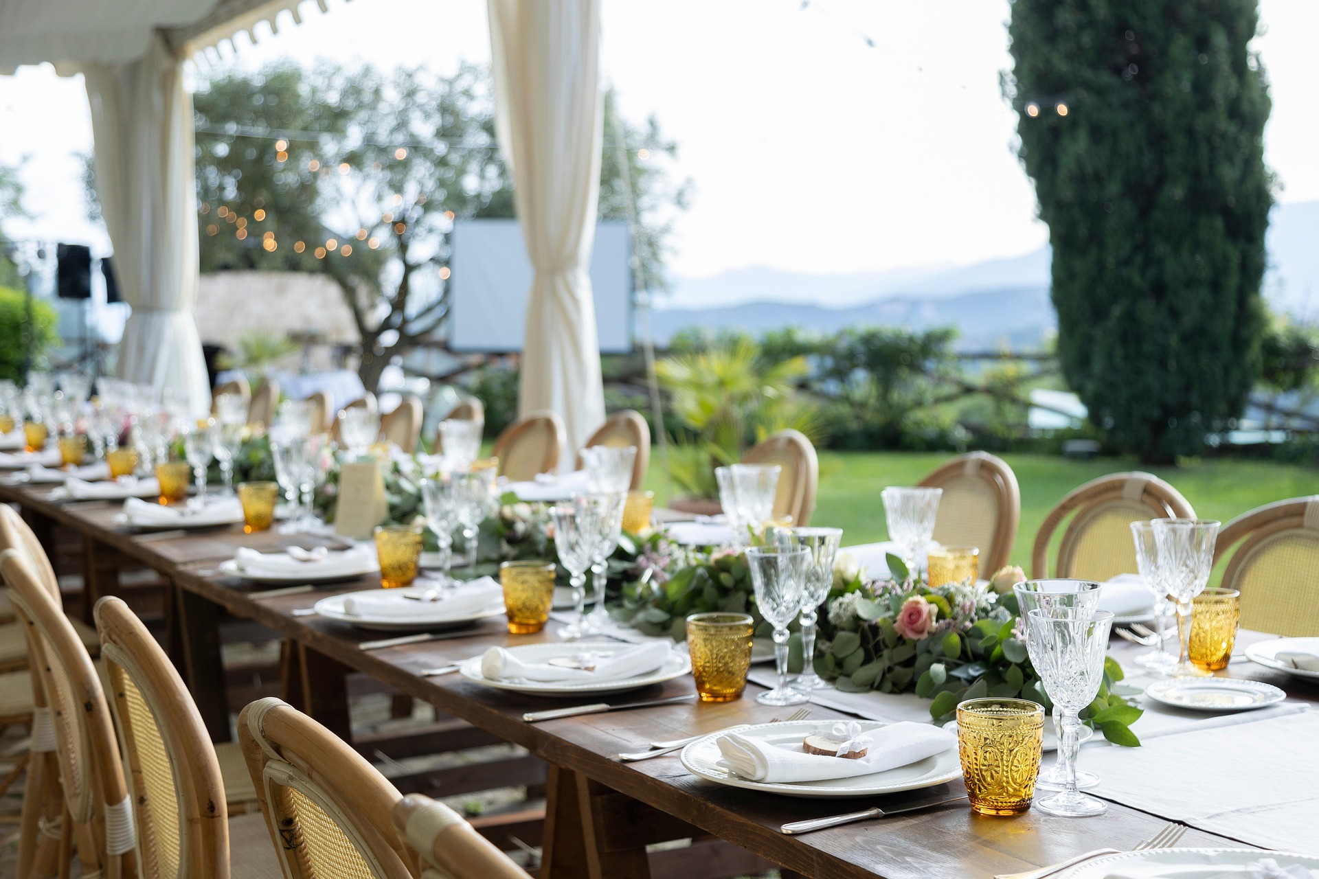 Long outdoor wedding banquet table with garland centerpiece and set places, planned with GuestSeater AI seating planner
